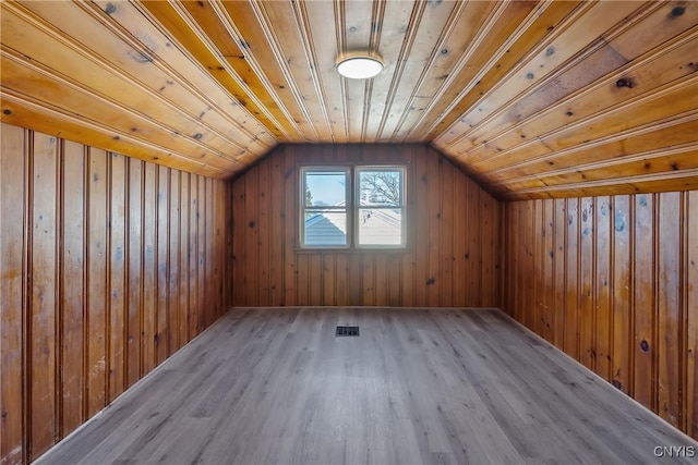 bonus room featuring vaulted ceiling, light wood-type flooring, wood ceiling, and wood walls