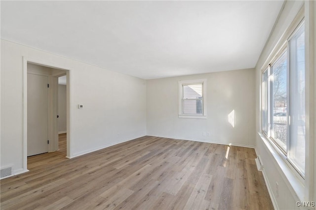 empty room with plenty of natural light and light hardwood / wood-style floors