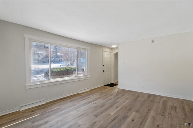 unfurnished room featuring light wood-type flooring and baseboard heating