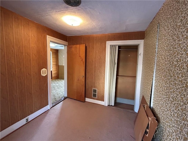 unfurnished bedroom featuring wooden walls and a closet