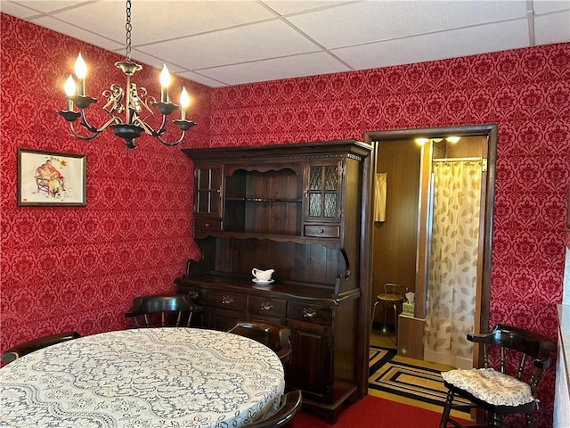 dining space with a drop ceiling and a chandelier