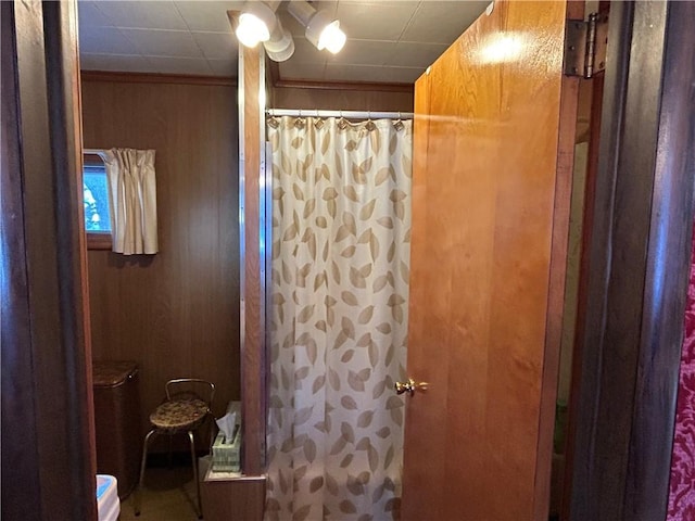 bathroom featuring curtained shower and wood walls