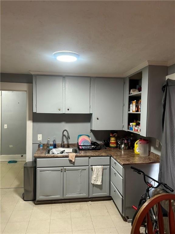 kitchen featuring light tile patterned flooring, gray cabinets, and sink