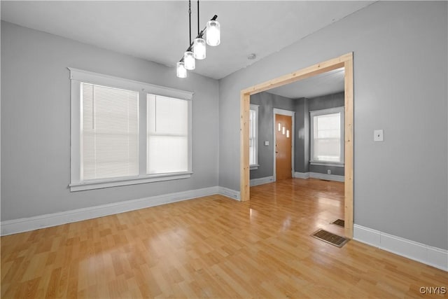 unfurnished dining area featuring hardwood / wood-style flooring, a chandelier, and a wealth of natural light