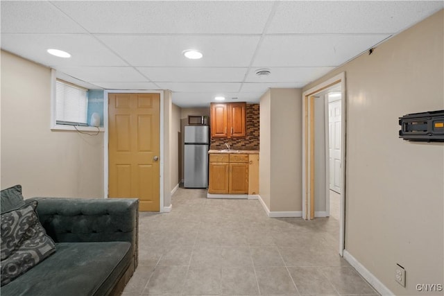 living room featuring sink, a paneled ceiling, and light tile patterned flooring