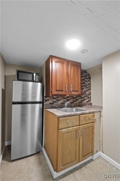 kitchen featuring appliances with stainless steel finishes, sink, decorative backsplash, and light tile patterned floors