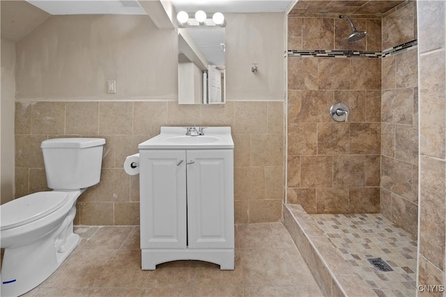 bathroom featuring tiled shower, vanity, toilet, and tile walls