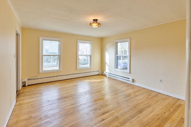 empty room featuring a baseboard heating unit and light hardwood / wood-style flooring