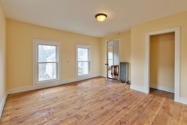 unfurnished living room with radiator heating unit and light hardwood / wood-style floors