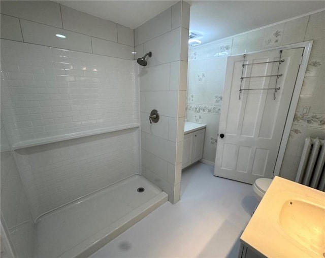 bathroom with vanity, tiled shower, radiator heating unit, and toilet