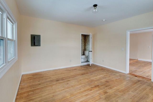 spare room featuring electric panel and light wood-type flooring