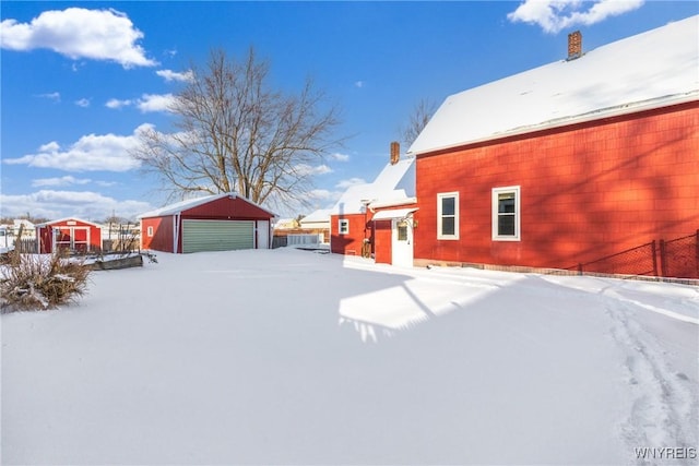 yard layered in snow featuring a garage and an outdoor structure