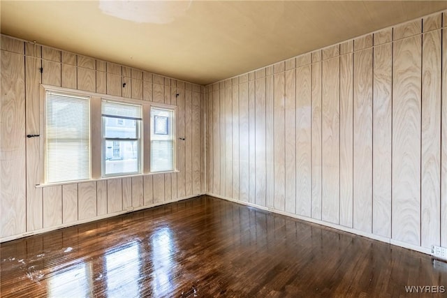 unfurnished room with dark wood-type flooring and wood walls