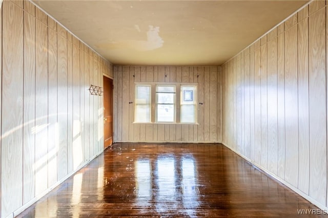 unfurnished room featuring dark hardwood / wood-style flooring and wooden walls