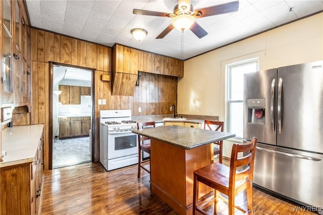 kitchen with a kitchen island, white gas range, sink, a breakfast bar area, and stainless steel fridge with ice dispenser