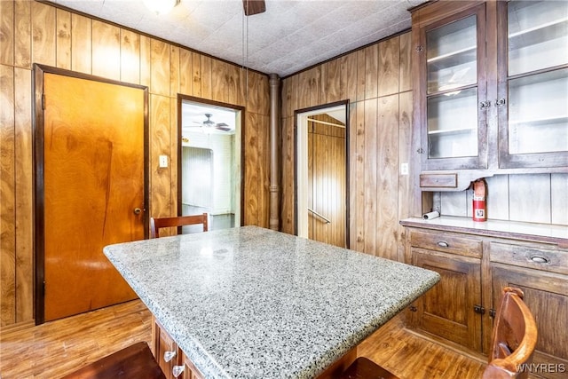 kitchen with wood walls, ceiling fan, and a kitchen bar