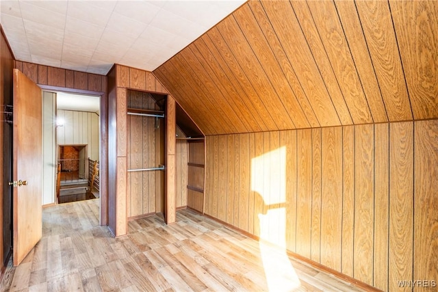 bonus room with vaulted ceiling, light hardwood / wood-style flooring, and wood walls