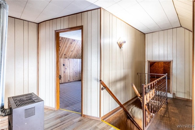 stairway featuring vaulted ceiling and wood walls