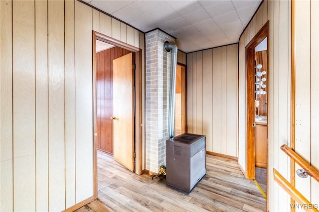 corridor with light hardwood / wood-style floors and wood walls