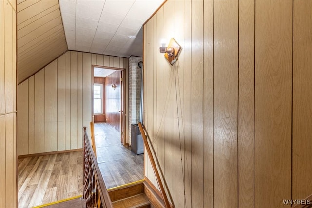 stairs with lofted ceiling, wooden walls, and wood-type flooring