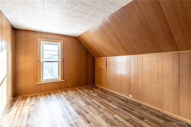 bonus room featuring wood walls, lofted ceiling, and light wood-type flooring