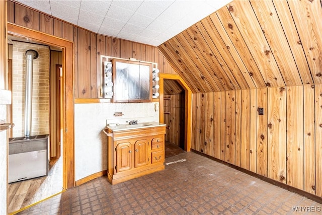 bathroom with lofted ceiling, vanity, and wood walls