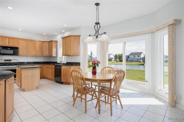 kitchen featuring a water view, decorative light fixtures, light tile patterned floors, and black appliances