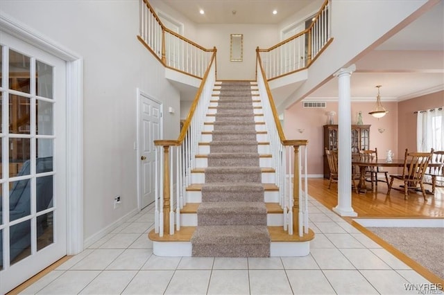 staircase featuring crown molding, decorative columns, and tile patterned floors