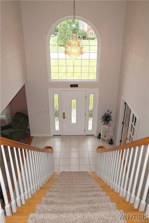 entrance foyer featuring a towering ceiling, light tile patterned floors, and a chandelier