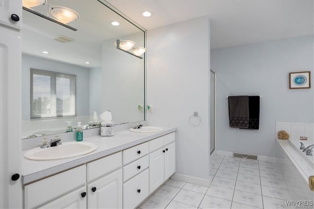 bathroom with vanity and tiled bath