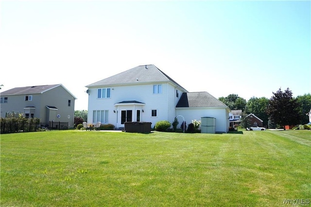 back of house with a hot tub and a lawn