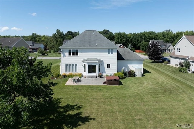 rear view of property featuring a yard, a hot tub, and a patio