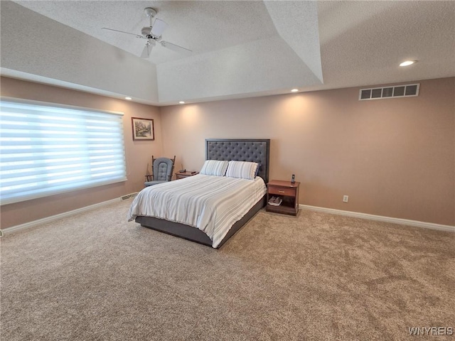 carpeted bedroom featuring ceiling fan, a raised ceiling, and a textured ceiling