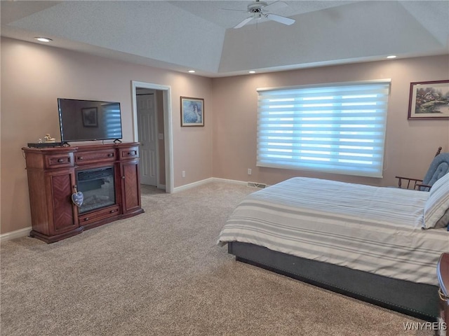 bedroom with a tray ceiling, light colored carpet, and ceiling fan