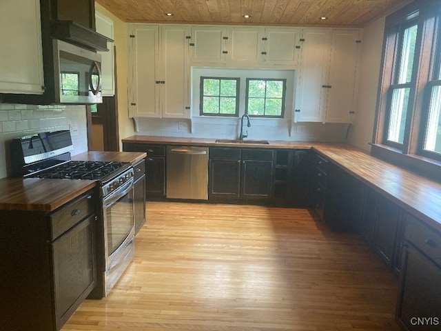 kitchen with stainless steel appliances, white cabinetry, sink, and butcher block countertops