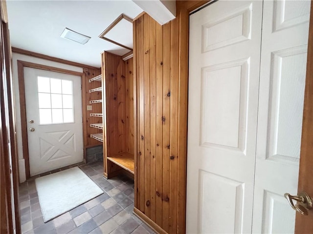 mudroom featuring ornamental molding and wood walls