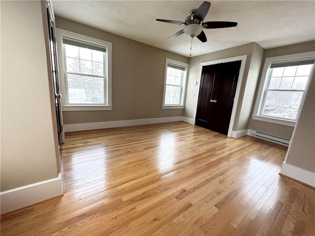 unfurnished bedroom with light hardwood / wood-style flooring, a closet, ceiling fan, and baseboard heating