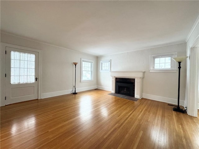 unfurnished living room featuring ornamental molding and light wood-type flooring