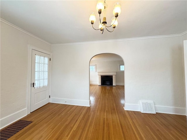 interior space with hardwood / wood-style floors, a notable chandelier, ornamental molding, and a healthy amount of sunlight