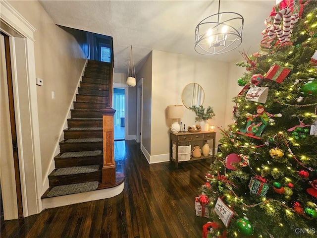 stairs featuring wood-type flooring and an inviting chandelier