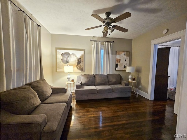 living room with ceiling fan, dark wood-type flooring, and a textured ceiling