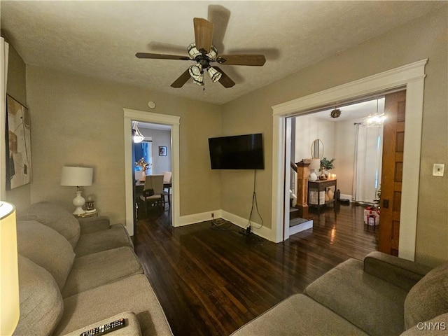 living room featuring ceiling fan, dark wood-type flooring, and a textured ceiling