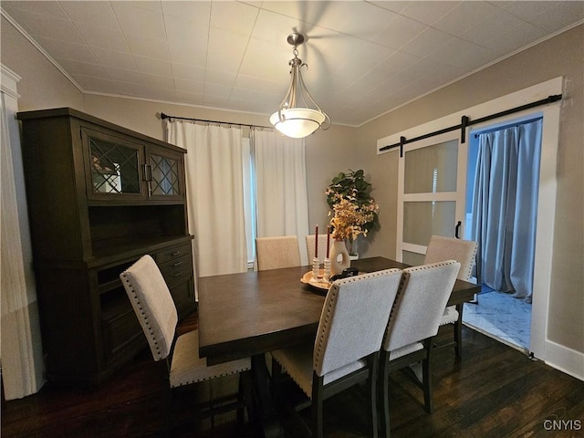 dining area featuring crown molding, a barn door, and dark hardwood / wood-style flooring