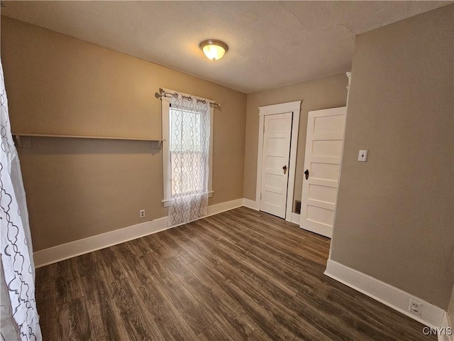 unfurnished room with dark wood-type flooring and a textured ceiling