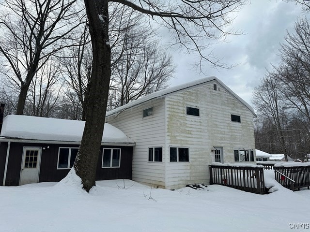 snow covered back of property featuring a deck