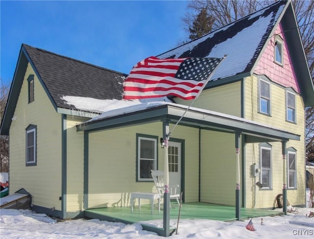 snow covered house featuring covered porch