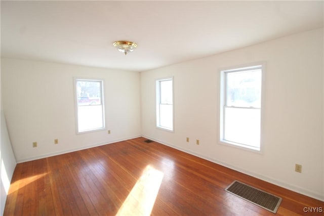 empty room featuring a healthy amount of sunlight and dark hardwood / wood-style floors