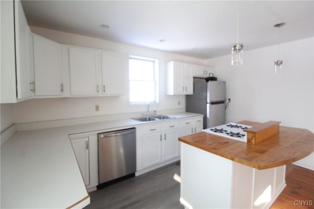 kitchen featuring pendant lighting, sink, appliances with stainless steel finishes, a center island, and white cabinets