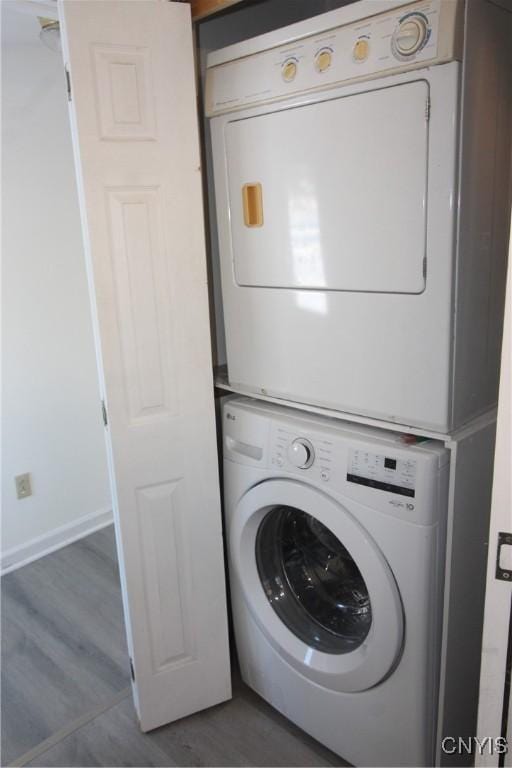 washroom featuring dark hardwood / wood-style flooring and stacked washer / drying machine