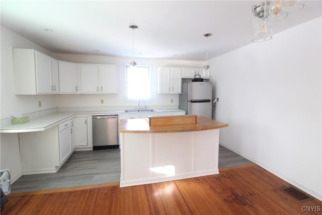 kitchen with sink, white cabinetry, a center island, appliances with stainless steel finishes, and hardwood / wood-style floors